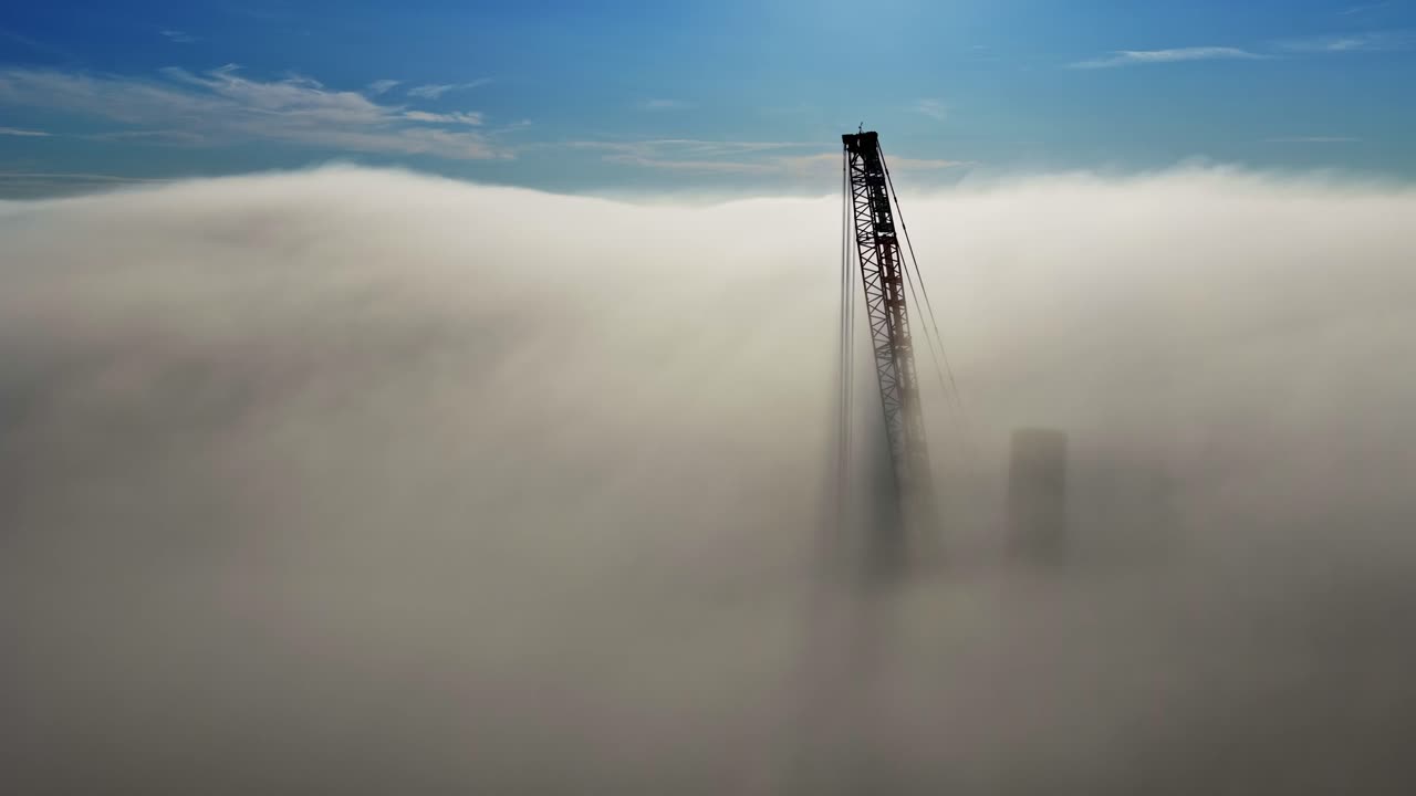 A towering structure rises above dense clouds, creating a mysterious mood