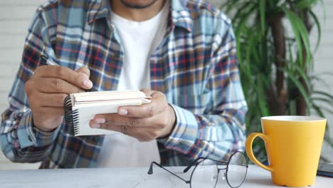hombre escribiendo en el bloc de notas en el escritorio