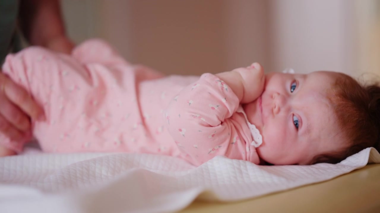 Bambino sdraiato su un lettino imbottito per trattamenti mentre gli adulti sostengono e muovono delicatamente il bambino durante una sessione di terapia pediatrica