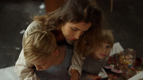 Creative-family-spending-time-in-workshop.-Girl-showing-tools-to-son-in-studio.