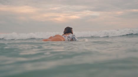 A woman is captured paddling on a surfboard in the calm waters of Santa Teresa, Costa Rica