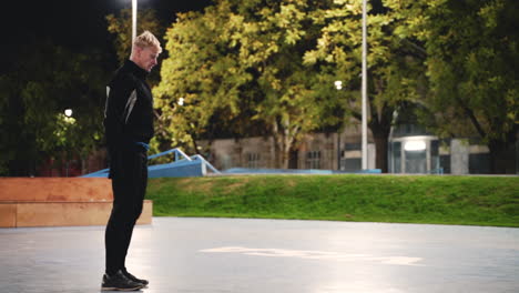 Sportlicher-Blonder-Mann,-Der-Sich-Vor-Dem-Training-Im-Park-Nachts-Die-Beine-Streckt-Und-Ausfallschritte-Macht