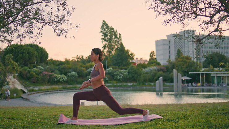 Sporty woman practicing asana raising up hand at sunset park. Yoga lady training