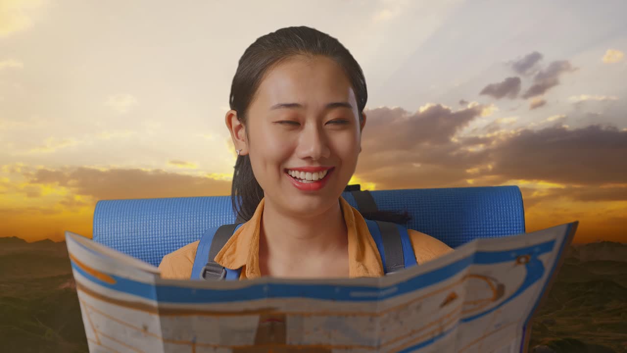 Close Up Of Asian Female Hiker With Mountaineering Backpack Looking At The Map Then Smiling To Camera While Standing On The Top Of Mountain During Sunset Time