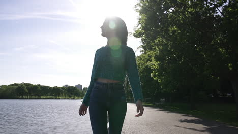 beautiful italian girl walking peacefully in a tranquil park wearing a shimmery sweater in london, united kingdom
