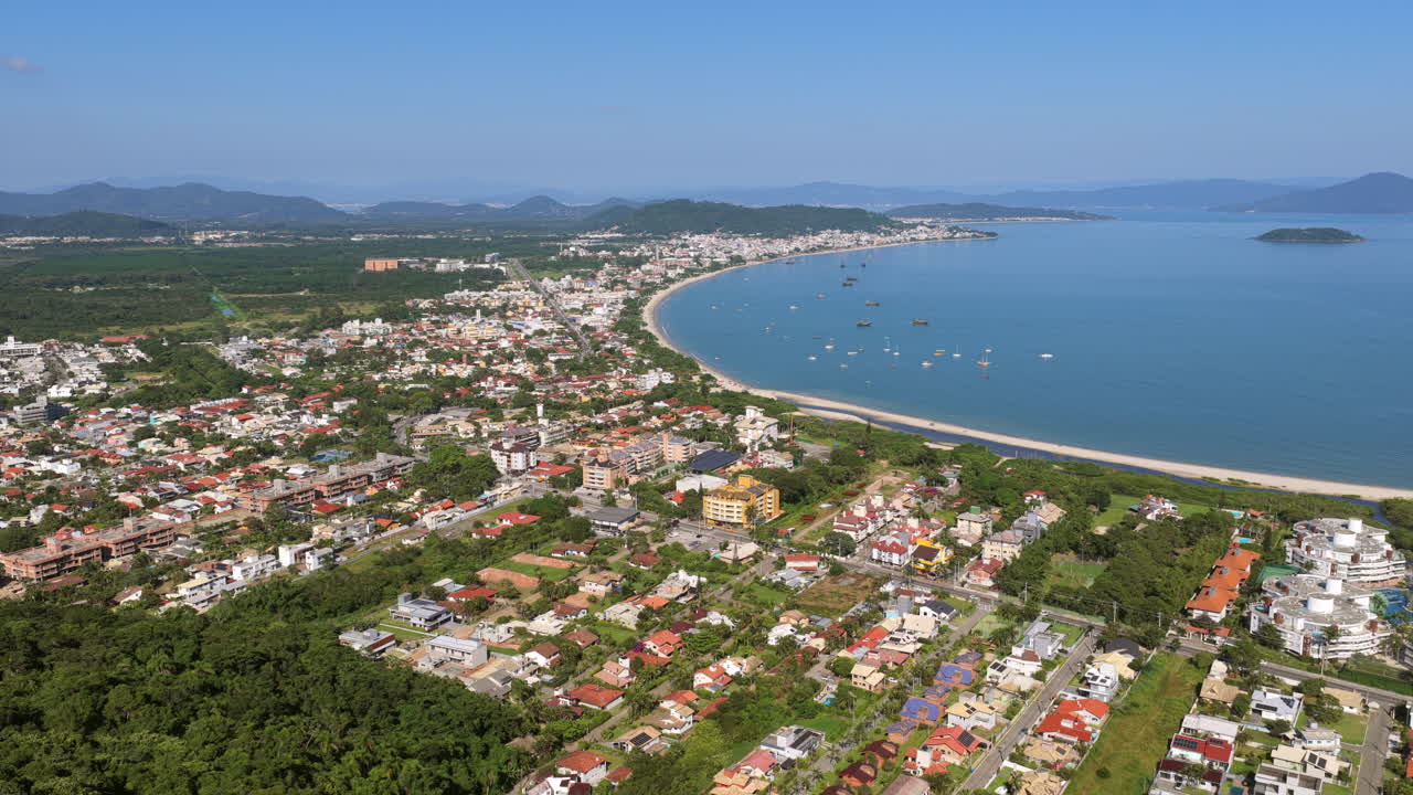 Pemandangan udara Praia Cachoeira do Bom Jesus di Florianopolis, Brasil dengan pantai melengkung, garis pantai, dan area perumahan