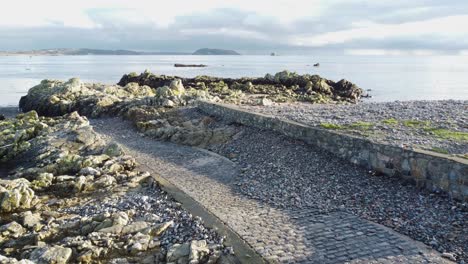 Bordeaux-Harbour-Guernsey-flight-down-cobbled-causeway-looking-out-across-Little-Russell-Channel-to-Herm-and-Jethou-with-late-afternoon-sunlight