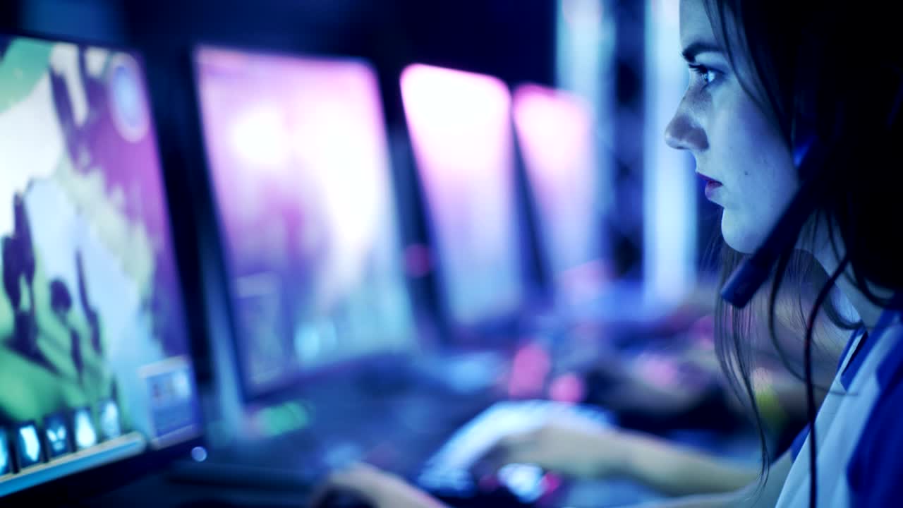 los jugadores profesionales se ponen auriculares y comienzan a jugar en el videojuego de estrategia mmorpg en sus computadoras. el equipo participa en el torneo de juegos cibernéticos en línea jugando en un café de internet.