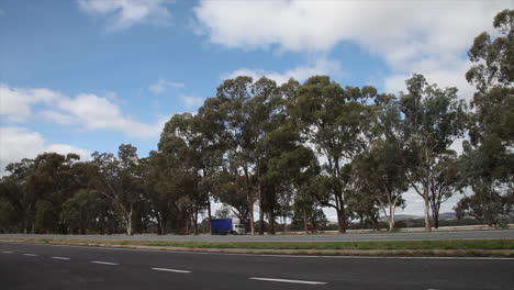 Vehicles-driving-into-shot-along-a-large-high-way-in-rural-Australia