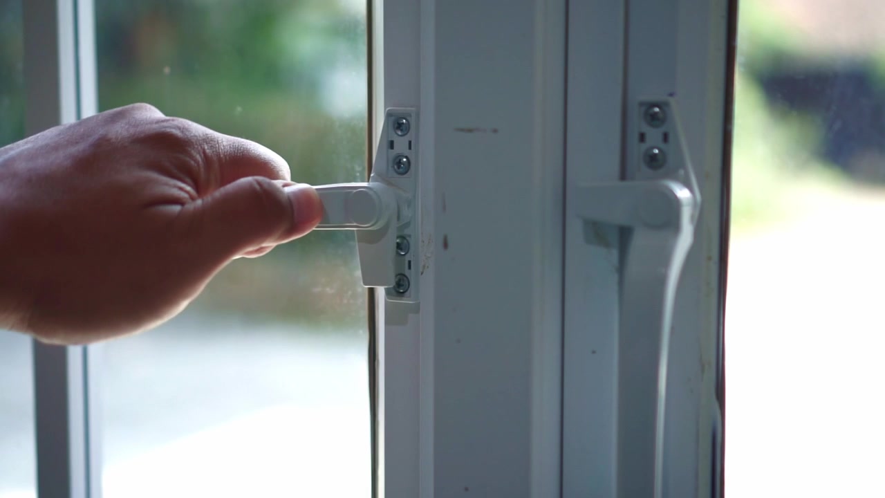 hand closing a modern window handle in a bright home interior. Concept of home security, ventilation control, and residential living.