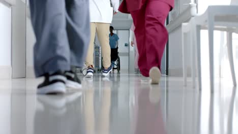 low section of diverse doctors walking in corridor at hospital, slow motion