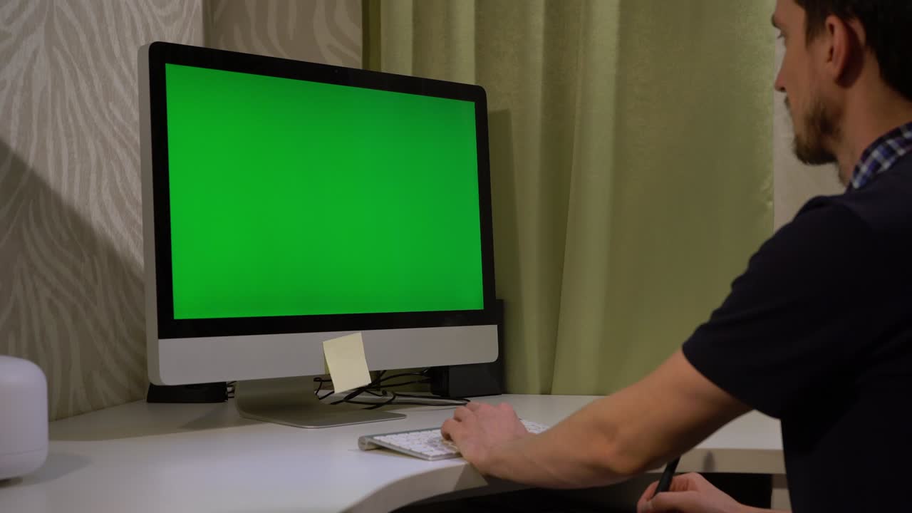 한 젊은이가 녹색 화면의 모니터 앞에 키보드에서 타이핑하고 있다