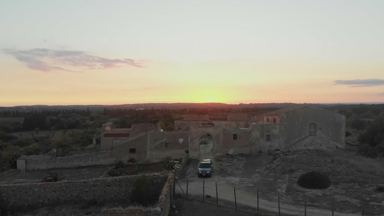 Vista aerea di una vecchia villa abbandonata e di un'auto che risplendono al tramonto a Catania, Sicilia, Italia