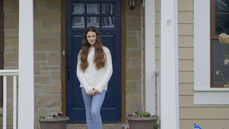 girl standing on porch at home looks into camera, medium shot