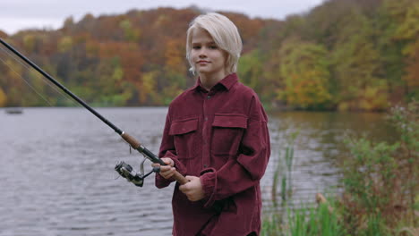 a young boy fishing by a lake in autumn