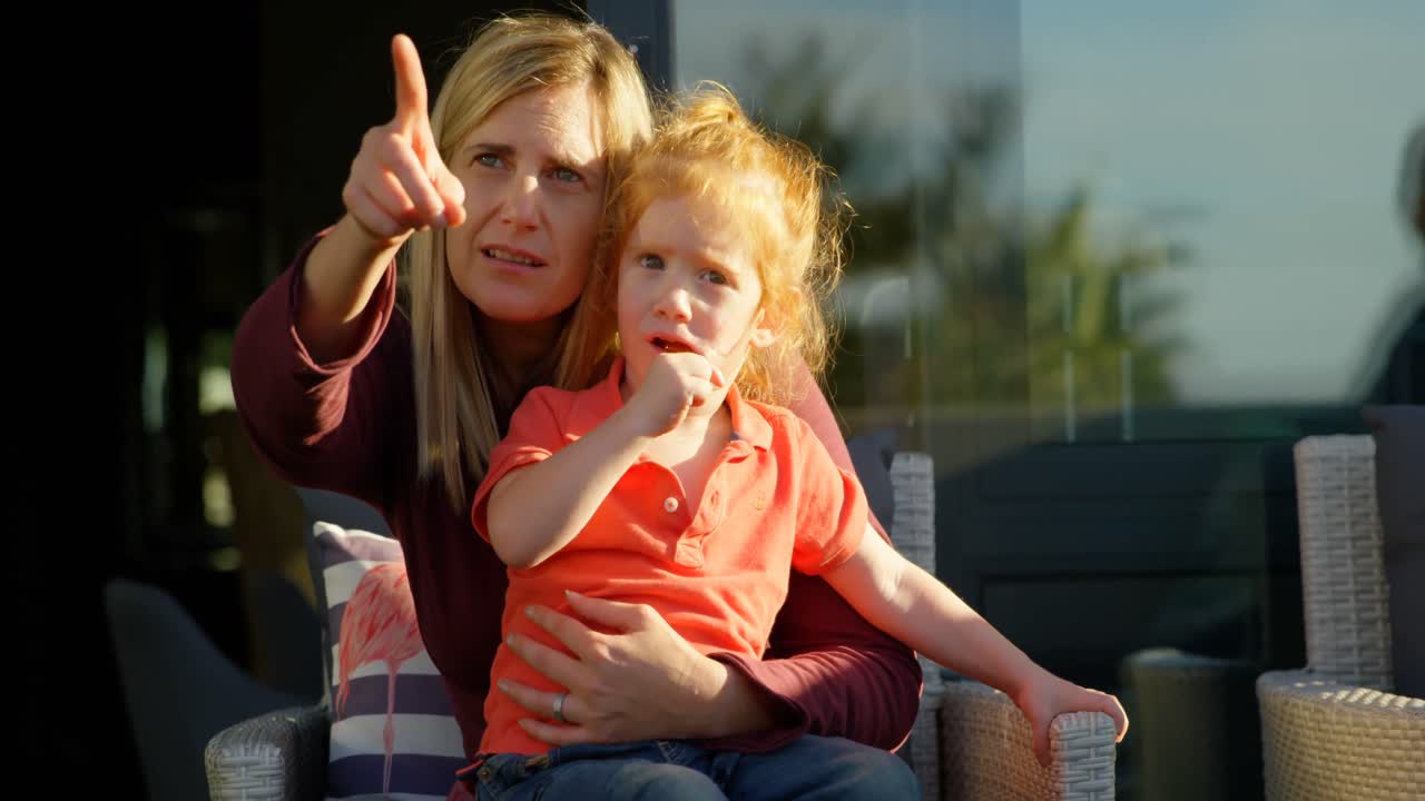 Madre che indica con la mano per mostrare al figlio sul balcone 4k