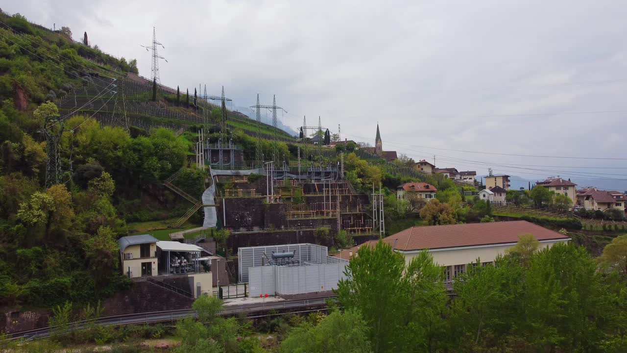 Aerial shot of Bolzano, Italy, featuring power lines, scenic hills, and buildings.