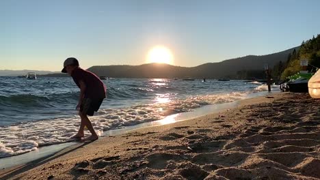 Niño-Llenando-Un-Balde-De-Playa-Amarillo-Con-Agua-De-La-Costa-Que-Se-Estrella