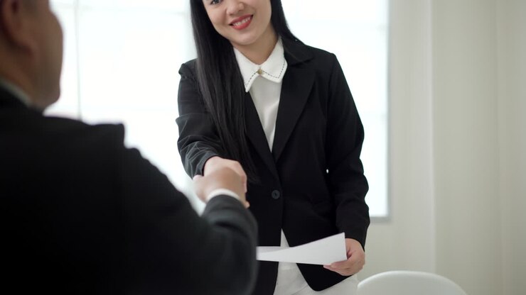 Smart asian woman shakes hands to greet a HR staff before a job interview to apply for a job. Happy woman seeker or insurance broker presenting a business deal. Business woman sending resume.