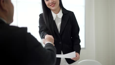 smart asian woman shakes hands to greet a hr staff before a job interview to apply for a job. happy woman seeker or insurance broker presenting a business deal. business woman sending resume.