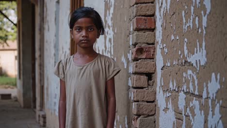 vulnerable young girl standing near dilapidated wall, embodying childhood hardship and emotional depth with contemplative gaze reflecting social inequality and unspoken struggle