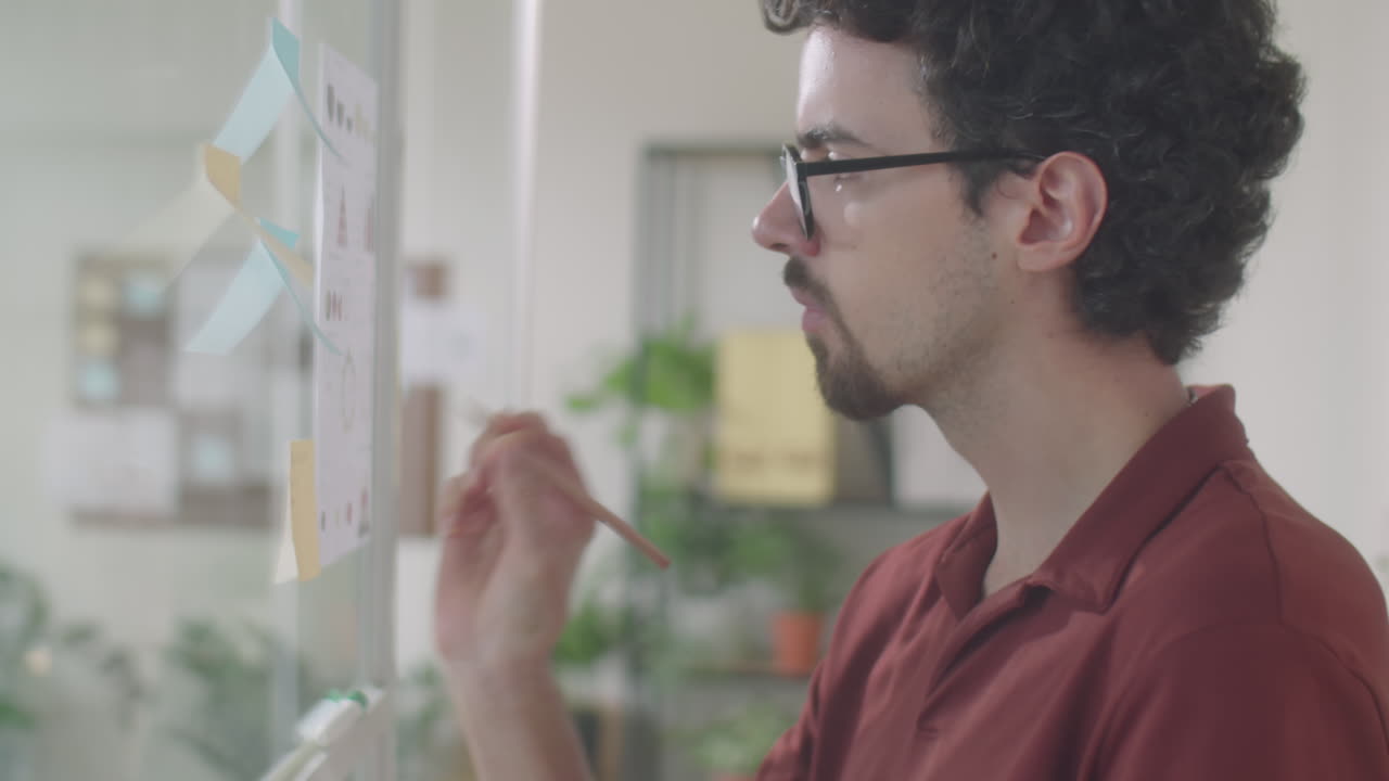 Office Worker Writing on Sticky Notes Attached to Glass Wall