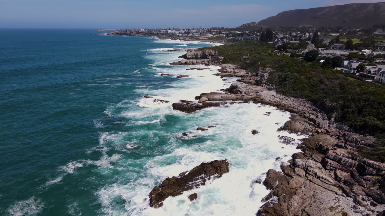 vuelo cinematográfico de drones sobre la escarpada costa de hermanus con olas golpeando rocas - histórico pueblo de pescadores en la costa de ballenas del cabo