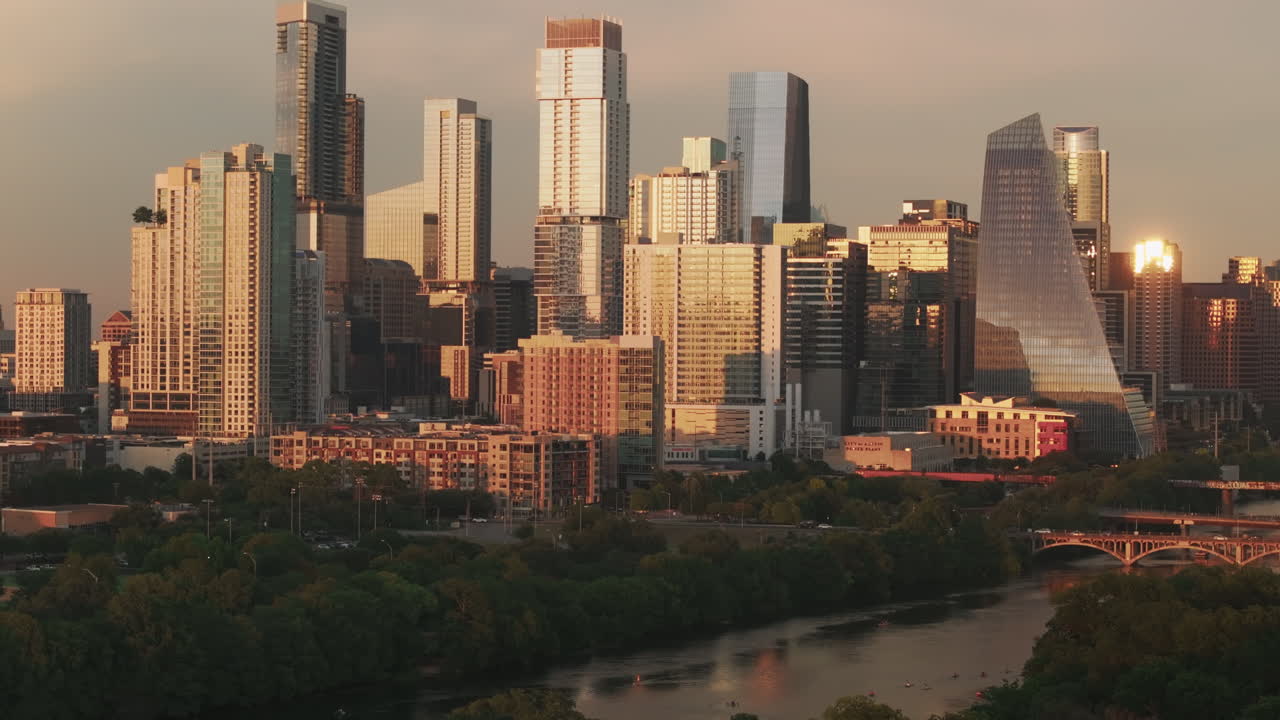 Drone slowly rises from Zilker Park to reveal a close-up view of Downtown Austin. The shot highlights modern architecture, warm tones, and lush greenery in a cinematic aerial composition