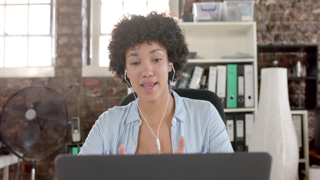 Happy biracial casual businesswoman having laptop video call in office in slow motion