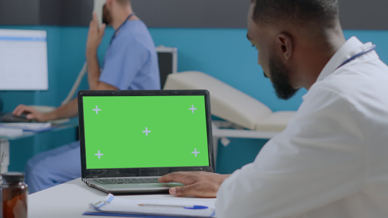 Doctor using laptop with green screen in hospital