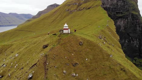 4k aerial beautiful parallax of famous lighthouse, kalsoy in the landscape kallur at the faroe islands with seagulls flying about on a cloudy day