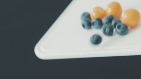 different berries falling down a chopping board