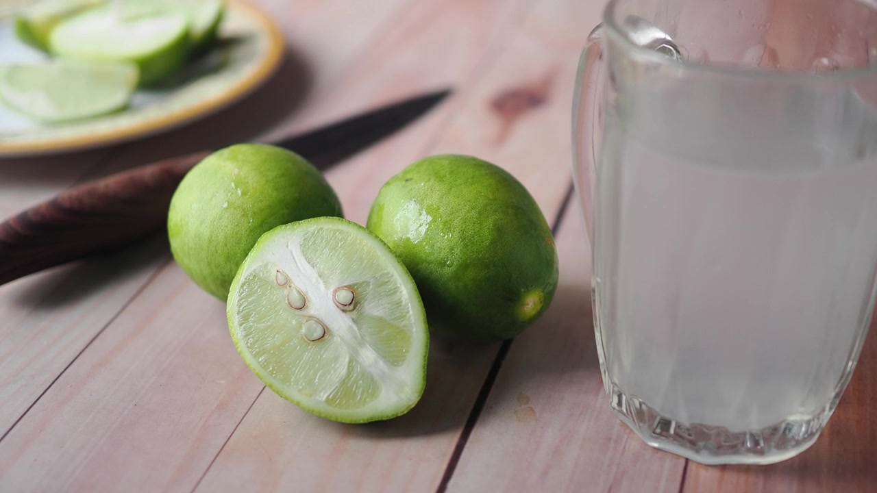 Friske limefrugter og et glas limesaft på et træbord