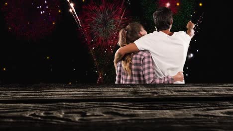 Animation-of-fireworks-over-back-view-of-caucasian-couple-on-black-background