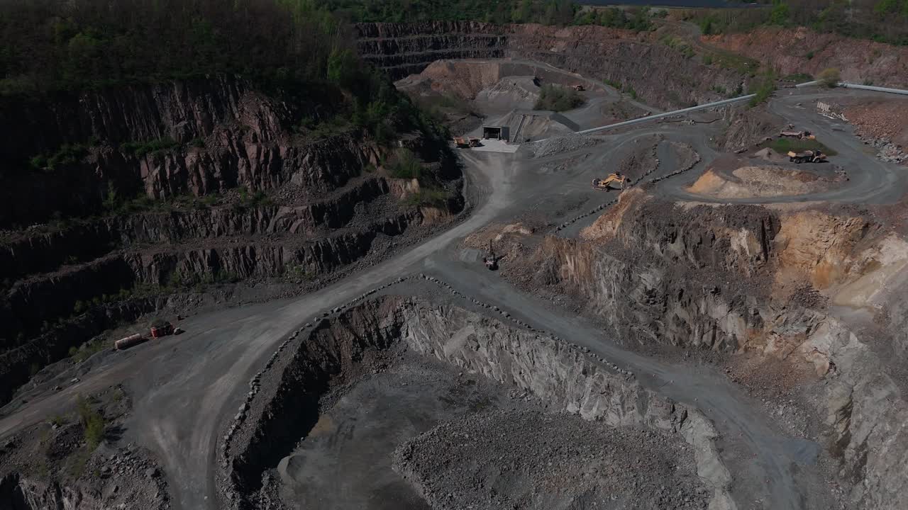 Drone shot over a large stone quarry near Wurzen, Germany. Shows excavation zones, raw terrain, and industrial structures. Ideal for construction, industry, and geology topics.