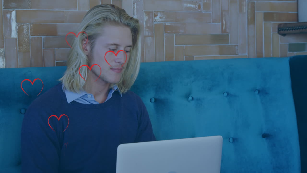Animation of heart icons over caucasian businessman using laptop