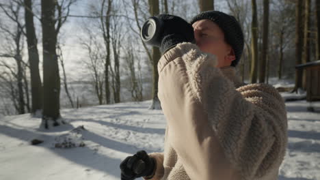 person in winter attire enjoying a hot drink outdoors on a snowy day warming up in the cold and enjoying nature