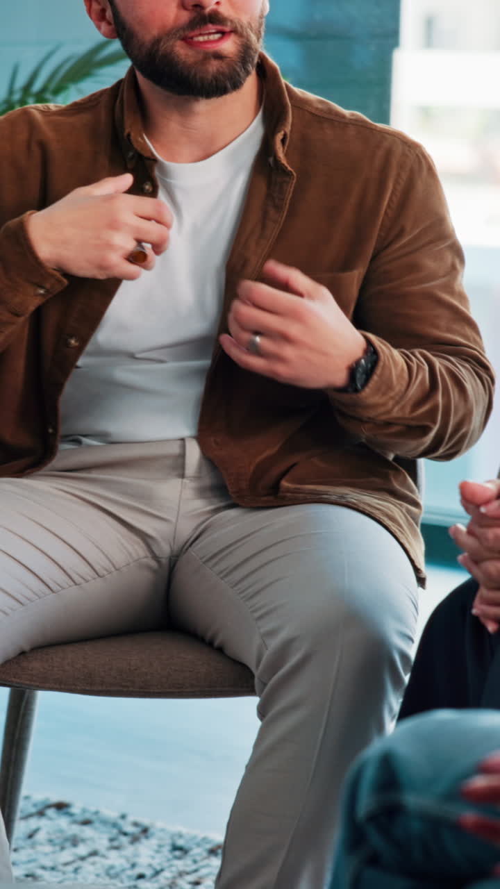 Mand, der sidder indendørs iført en brun jakke og beige bukser