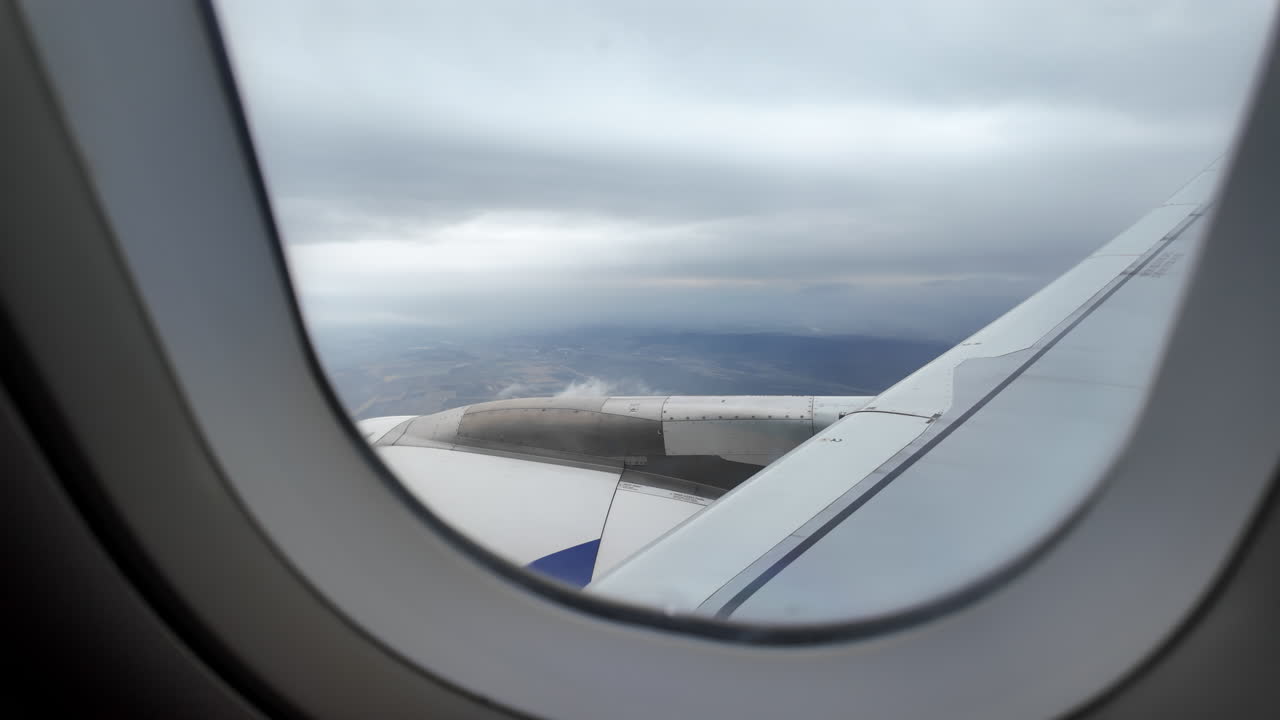 View from an airplane window of houses and fields while a plane is preparing to land
