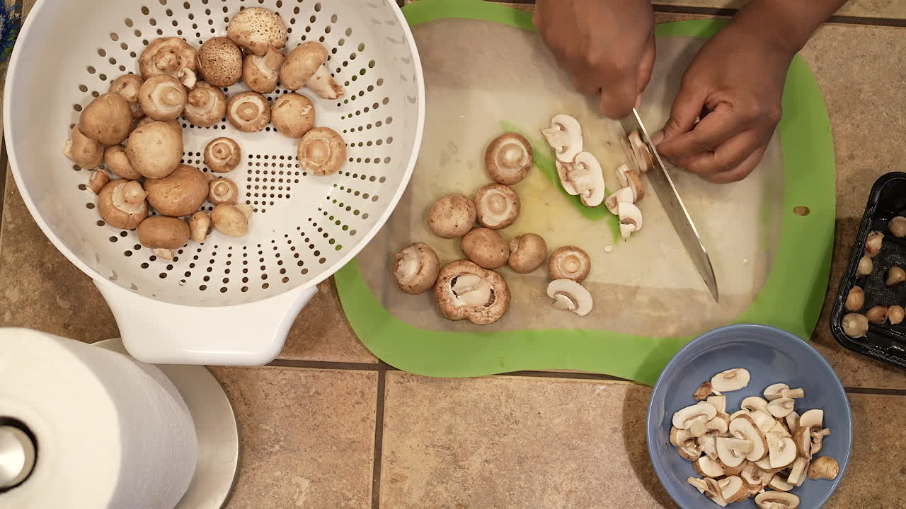 Slicing organic cremini mushrooms for a homemade soup recipe - overhead view WILD RICE SERIES