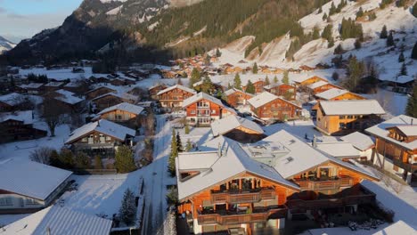 casas de la ciudad debajo de las escarpadas montañas de los alpes en la nieve y la luz del sol de invierno