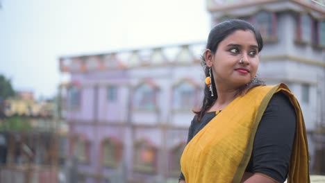 a beautiful young romantic married indian woman roaming on the roof and looking away and smiling