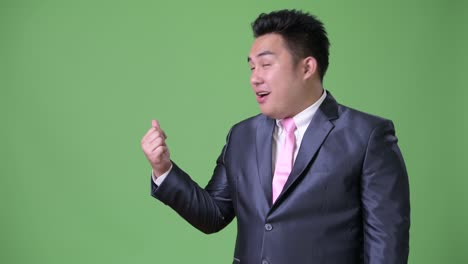 초록색 배경에 젊은 잘생긴 과체중 아시아 사업가