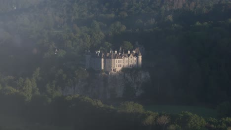 Walzin-castle-reveal-in-the-clouds-on-natural-cliff,-aerial