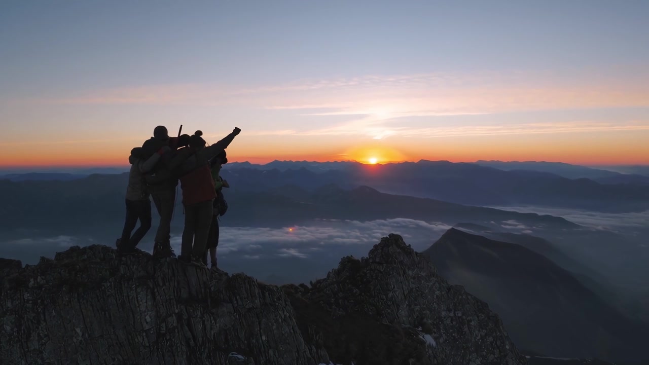 Sagome di escursionisti che festeggiano su una cima di montagna all'alba.