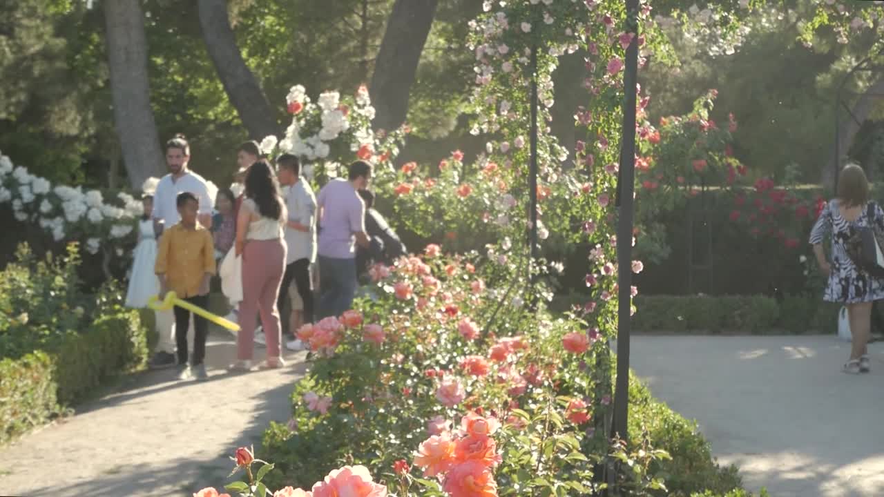 A colourful flowery scene with people and children visiting La Rosaleda, Retiro Park in spring. Vibrant and picturesque garden scene.