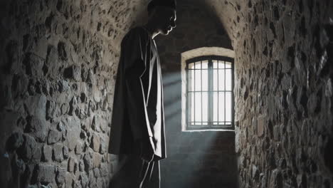 man walking in a dark stone prison cell