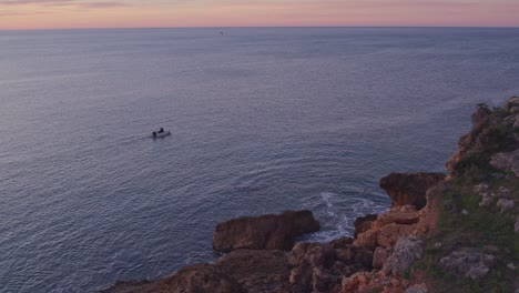 Local-fisherman-is-looking-for-fish-near-Praia-dos-Arrifes-Portugal,-aerial