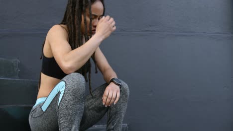 vista lateral de una joven mujer afroamericana relajándose en los escalones de la ciudad 4k
