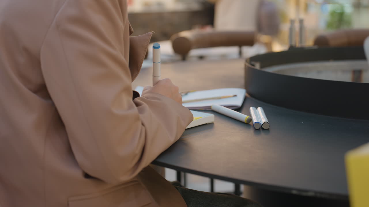 caucasian woman organizing her schedule publicly, closeup of lady jotting notes amid shopping area activities, woman surrounded by shopping bags and writing in her planner at mall table